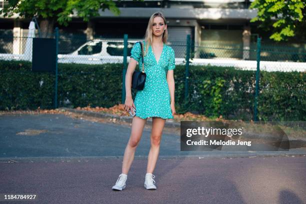 Model Rebecca Leigh Longendyke wears a green print summer dress, black Chanel bag, and white Converse sneakers after the Miu Miu Resort 2020 show on...