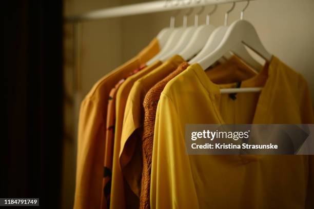 yellow clothes hanging on a coathangers on a clothing rack - hanging blouse stock pictures, royalty-free photos & images