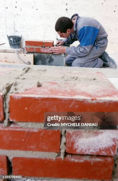 Photo prise le 24 novembre 2004 à Caen d'un élève de première année du secteur maçonnerie apprenant les bases du métier pour réussir un mur en...