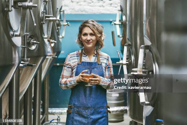 confident buenos aires craft beer expert standing in brewery - brewery tank stock pictures, royalty-free photos & images