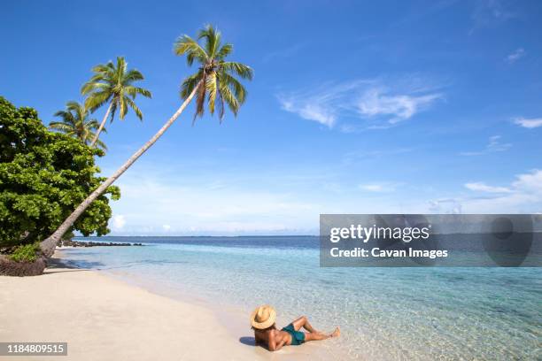 tanned fit man, wearing hat and bathingsuit, at tropical sandy beach - サモア ストックフォトと画像