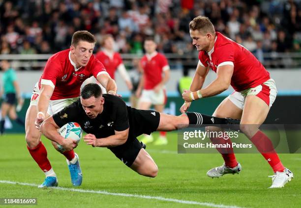 Ryan Crotty of New Zealand touches down to score his team's fifth try under pressure from Josh Adams and Hallam Amos of Wales during the Rugby World...