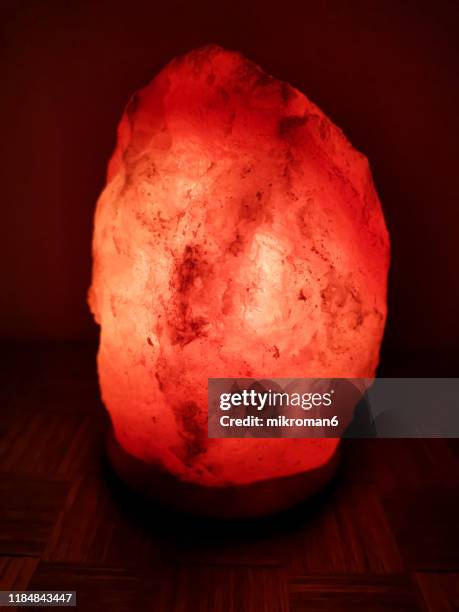 illuminated himalayan crystal salt lamp in darkroom - himalayazout stockfoto's en -beelden