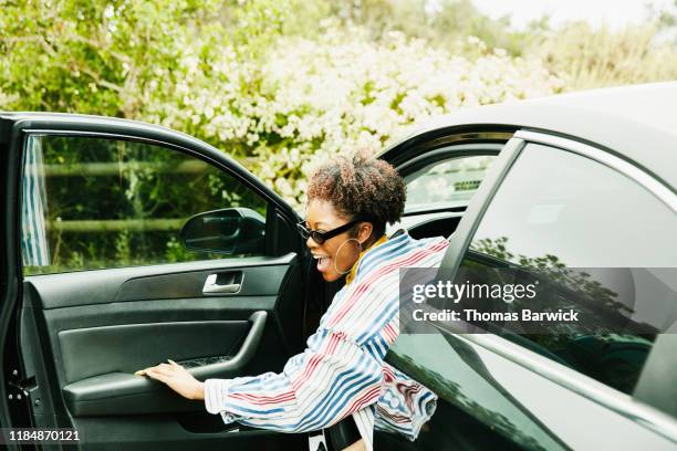 smiling woman stepping out of drivers seat after parking car - woman leaving fotografías e imágenes de stock