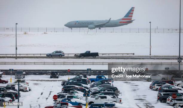 Jet passes snow-covered cars parked at Denver International Airport on November 26, 2019 in Denver, Colorado. Flights were delayed and rescheduled...