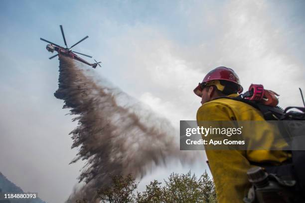 Firefighter watches a helicopter dropping fire retardant over the Cave Fire at Los Padres National Forest on November 26, 2019 in Santa Barbara,...