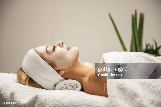 mooie vrouw met masker op gezicht in spa beauty salon - face pack stockfoto's en -beelden