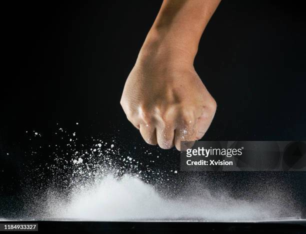 hand fist toward dancing flour with black background - ballet powder stock-fotos und bilder