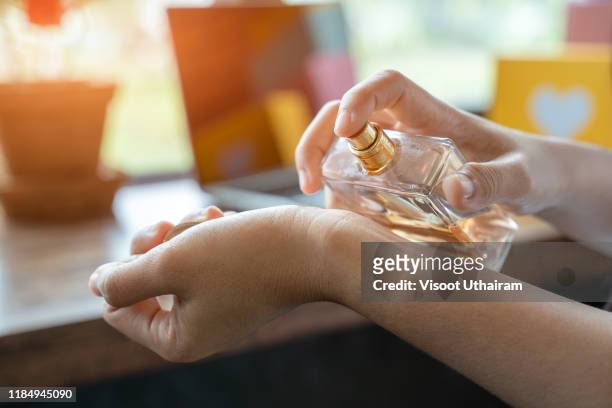 women applying perfume on her wrist. - magasin cosmétique photos et images de collection