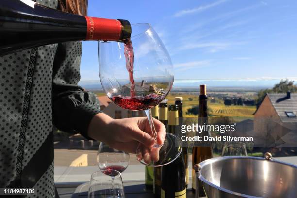 Anais Cattin serves Maison Joseph Cattin Rouge Pinot Noir Steinbach wine to visitors on the terrace of her family's winery on October 11, 2019 in the...