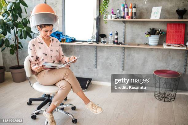 gemengde rasvrouwzitting onder haardroger in salon - haardroger stockfoto's en -beelden