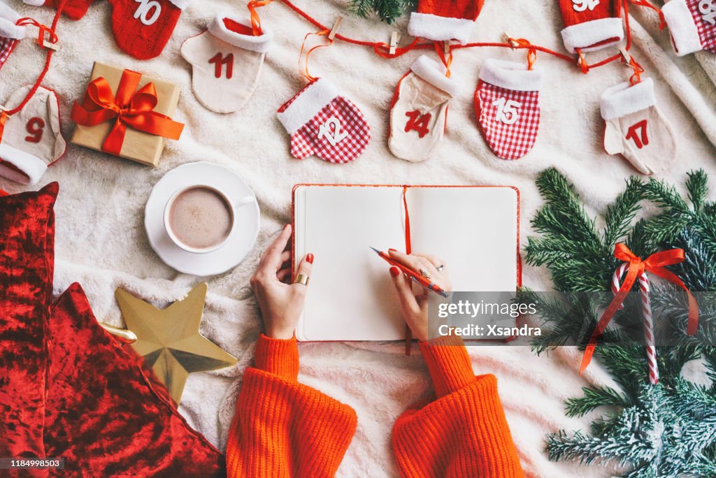 Woman writing in a blank notebook - Christmas concept flat lay