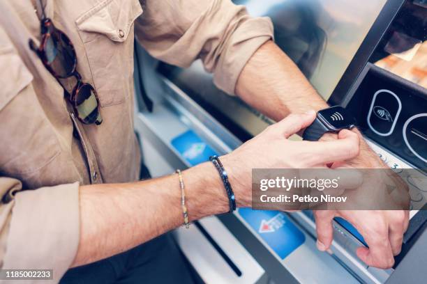 man making transactions at the atm with his smart watch - modern banking stock pictures, royalty-free photos & images
