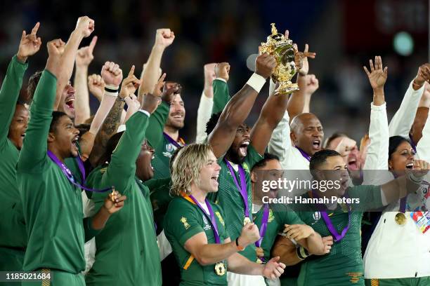 Players of South Africa celebrate as Siya Kolisi of South Africa holds the Web Ellis Cup following their victory against England in the Rugby World...