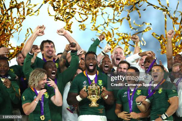 Players of South Africa celebrate as Siya Kolisi of South Africa lifts the Web Ellis Cup following their victory against England in the Rugby World...