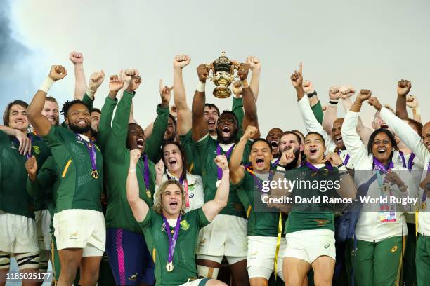 Players of South Africa celebrate as Siya Kolisi of South Africa lifts the Web Ellis Cup following their victory against England in the Rugby World...