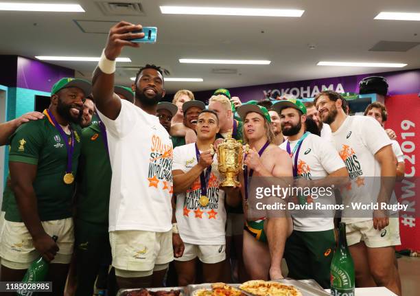 Siya Kolisi of South Africa takes a picture with his team mates and the Web Ellis Cup inside the dressing room following their team's victory against...