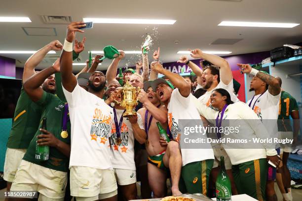 Siya Kolisi of South Africa takes a picture with his team mates and the Web Ellis Cup inside the dressing room following their team's victory against...