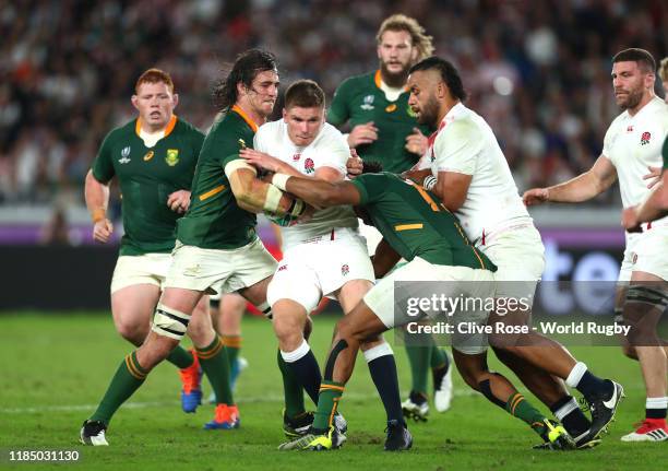 Owen Farrell of England is tackled by Franco Mostert and Lukhanyo Am of South Africa during the Rugby World Cup 2019 Final between England and South...