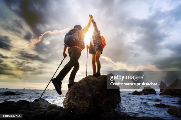 two climber helping to hike up . concept for success ,help,teamwork and leadership concept . - young man asian silhouette stock pictures, royalty-free photos & images