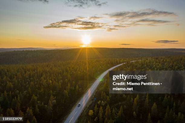 aerial view of the midnight sun shining over a remote road in the finnish lapland, with one solitary car on the road - inari finland bildbanksfoton och bilder