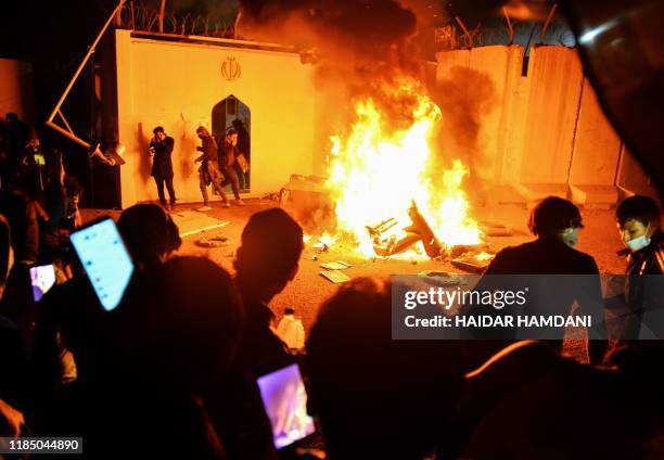 Iraqi demonstrators gather as flames start consuming Iran's consulate in the southern Iraqi Shiite holy city of Najaf on November 27 two months into...