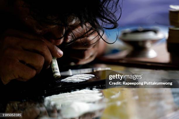 drug addict man sniffing cocaine lines on smart phone with rolled banknote. drug abuse concept. - cocaine 個照片及圖片檔