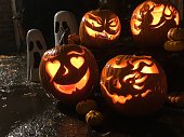 Cute Halloween Jack o’lantern pumpkins on rainy Halloween night
