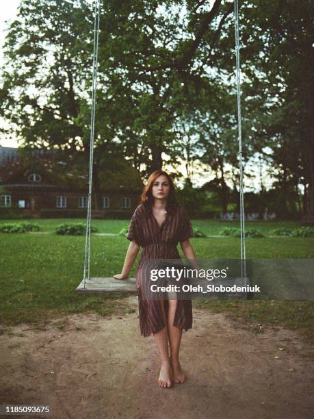 woman sitting on swing near old-fashioned mansion - latvian woman stock pictures, royalty-free photos & images