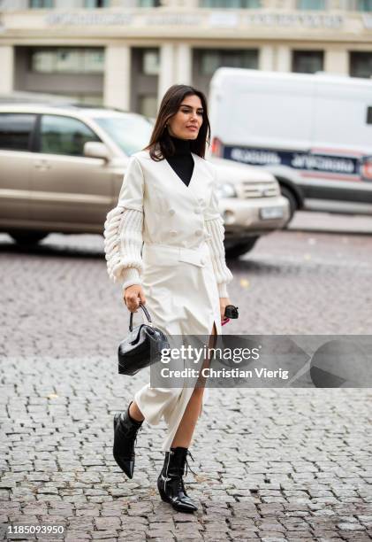 Asena Sarıbatur is seen wearing creme white coat, black laced boots, bag during day 3 of the Mercedes-Benz Tbilisi Fashion Week on November 02, 2019...