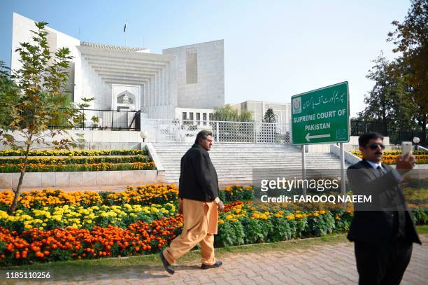Pakistani lawyer uses his mobile phone in front of the Supreme Court building during a case hearing suspending the notification of the tenure...
