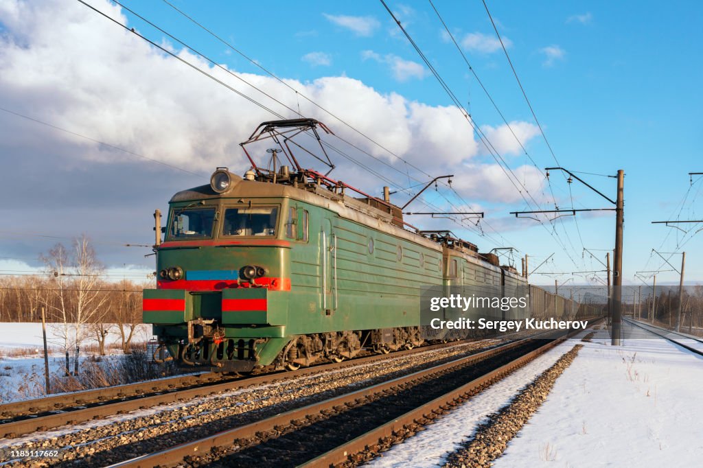 Powerful electric locomotive with freight train in a sunny spring day