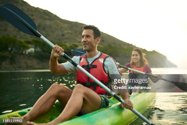 smiling spanish kayakers enjoying paddling at dawn - kayaking stock pictures, royalty-free photos & images