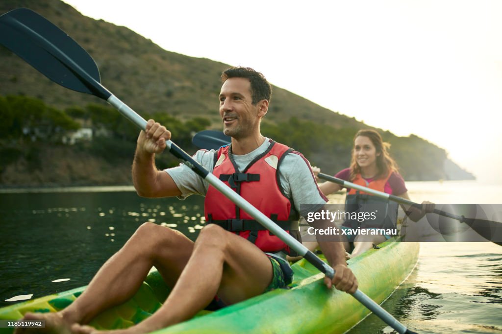 Kayakers espanhóis de sorriso que apreciam remar no alvorecer