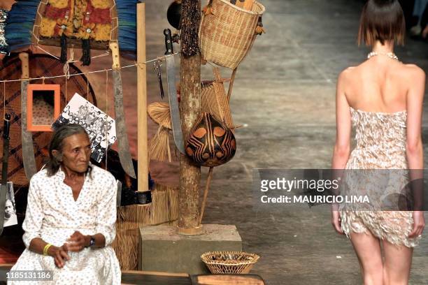 Model passes an unidentified indigenous woman who was born in Juazeiro del Norte, in north-east Brazil, a region affected by lack of rain. The model...