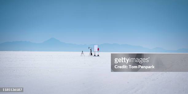 a panoramic image of a small movie set with tripod,  camera, and diffuser in the middle of white bonneville raceway salt flat with blue sky in the background. wendover, utah, usa - film set stock pictures, royalty-free photos & images