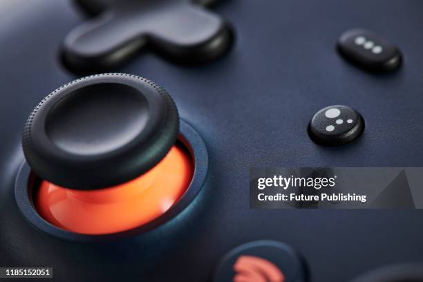 Close-up detail of the Google Assistant button and analogue control stick on a Google Stadia video game controller with a Night Blue finish, taken on...