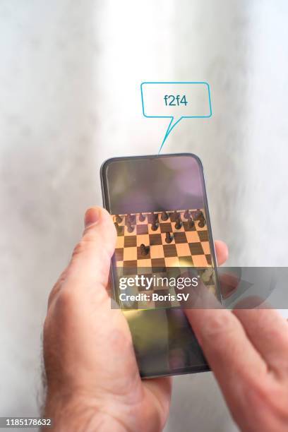 man playing mobile chess with online prompt - chess game stockfoto's en -beelden