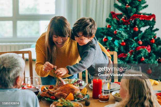 gelukkige moeder en haar zoon plezier hebben terwijl het houden van geroosterde kalkoen poot - eating food happy stockfoto's en -beelden