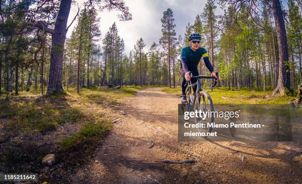 gravel road cyclist coming downhill on a narrow dirt road in the finnish lapland - offroad biking stock-fotos und bilder