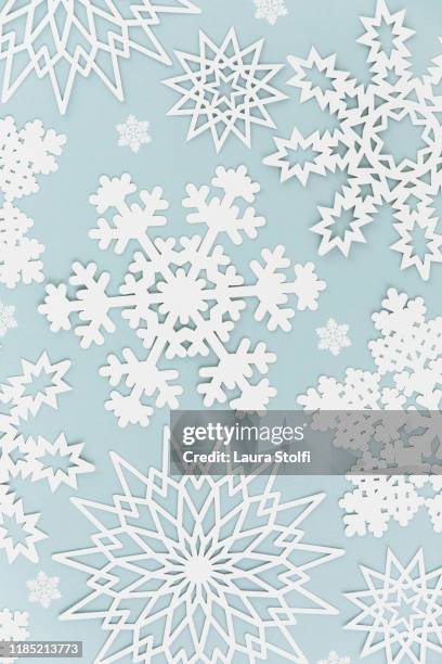 paper snowflakes in various shapes against pale blue background - paper snowflakes stock-fotos und bilder