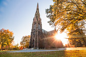 Beautiful Gothic Revival style cathedral at sunset, with golden warm light illuminating the fall foliage around the structure.