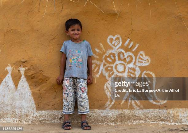 Portrait of a rajasthani boy standing in front of a decorated mud house, Rajasthan, Jaisalmer, India on July 22, 2019 in Jaisalmer, India.