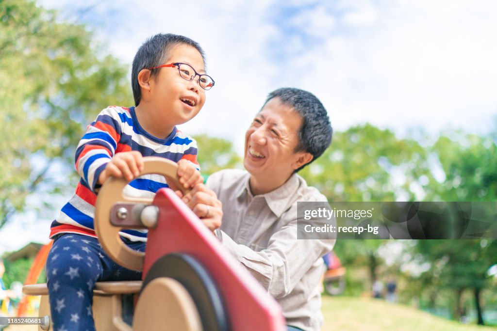 Child with down syndrome enjoying with his father at public park