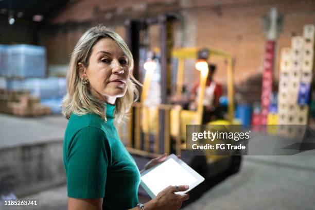 retrato de un empleado que sostiene una tableta digital en el almacén - mirar por encima del hombro mujer fotografías e imágenes de stock