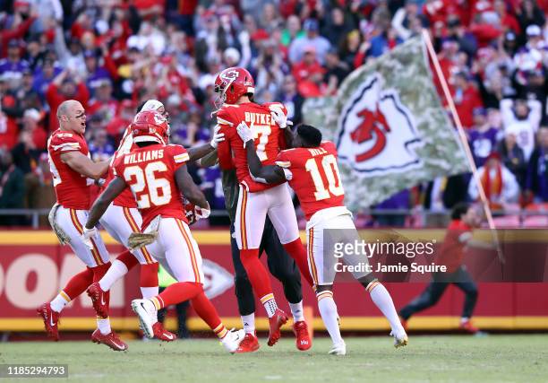 Kicker Harrison Butker of the Kansas City Chiefs is swarmed by players after kicking the game-winning field goal as the Chiefs defeat the Minnesota...