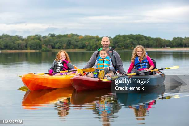 family in kayaks on lake - family red canoe stock pictures, royalty-free photos & images