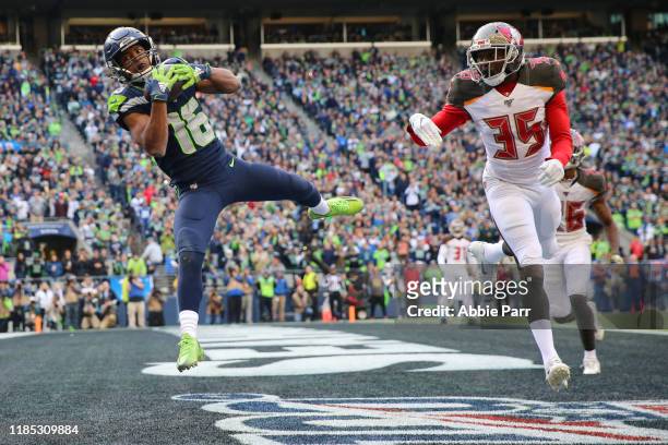 Tyler Lockett of the Seattle Seahawks scores a two-yard touchdown against Jamel Dean of the Tampa Bay Buccaneers in the third quarter during their...