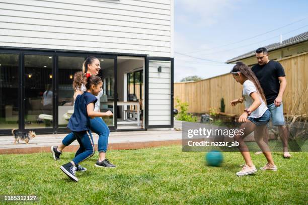 ouders spelen voetbal met kinderen in de achtertuin. - ball pit stockfoto's en -beelden