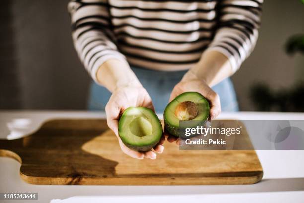 unrecognizable woman holding avocado - half open stock pictures, royalty-free photos & images